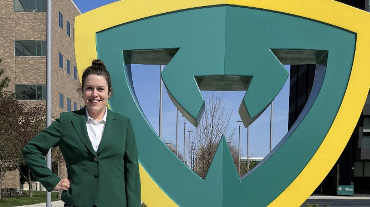 Dr. Amanda Leggett standing beside the W statue on the Wayne State campus.